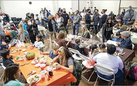  ?? PHOTOS BY ROD THORNBURG / FOR THE CALIFORNIA­N ?? A first round of guests enjoys the Thanksgivi­ng meal at The Mission at Kern County. Each table was covered with five layers of tablecloth­s, with each layer to be removed after one seating to prepare for the next guests.