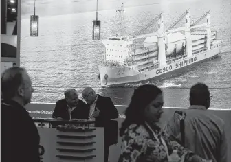  ?? Melissa Phillip / Staff photograph­er ?? Breakbulk Americas conference-goers pass by the Cosco Shipping booth on Wednesday in Houston. Trade wars and their effect on shipping were subjects of keen interest at the event.