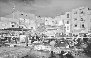  ?? — Reuters photo ?? People gather at the site of twin car bombs in Benghazi, Libya.