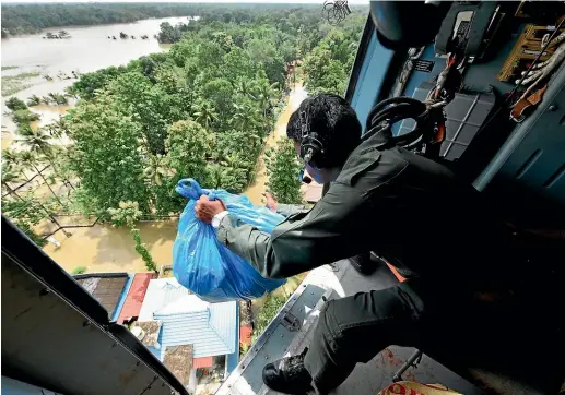  ?? AP ?? An Indian army soldier drops relief material from the air for stranded people at a flooded area in Chengannur in the state of Kerala.