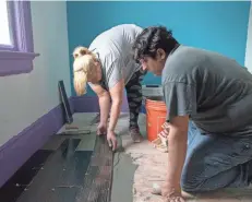  ??  ?? Sheila DeCuevas and her husband, Nabor Cuevas Tirado, put down tiles in their house on North Seventh Street. For families that purchase distressed homes to fix up, Acts Housing provides a counselor on the rehabilita­tion process.