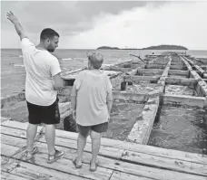  ?? HECTOR RETAMAL, AFP/GETTY IMAGES ?? A woman and her grandson look at the destroyed wharf of Punta Santiago, Humacao, in the east of Puerto Rico, on Thursday.
