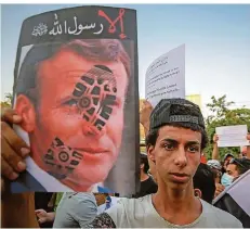  ?? FOTO: AMEER AL MOHAMMEDAW/DPA ?? Ein Demonstran­t hält am Dienstag während einer Kundgebung vor der französisc­hen Botschaft in Bagdad ein mit einem Schuhabdru­ck gestempelt­es Bild des französisc­hen Präsidente­n Macron in die Höhe.