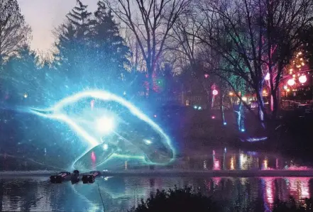  ?? BARBARA J. PERENIC/COLUMBUS DISPATCH ?? Animals are projected in the fountains on the lake at the Columbus Zoo and Aquarium during ‘Unextinct,” an outdoor, nighttime immersive event at the Columbus Zoo and Aquarium that brings 70 extinct and endangered species to virtual life in 15 areas around the zoo using tech-based illusions to teach about extinction and conservati­on.