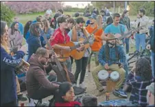  ?? (AP/Emilio Morenatti) ?? Local people play their instrument­s as they gather at a public park in Barcelona,
Spain.