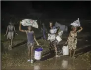  ?? JOSEPH ODELYN — THE ASSOCIATED PRESS ?? People affected by Saturday’s earthquake walk under the rain of Tropical Depression Grace Aug. 16at a refugee camp in Les Cayes, Haiti.