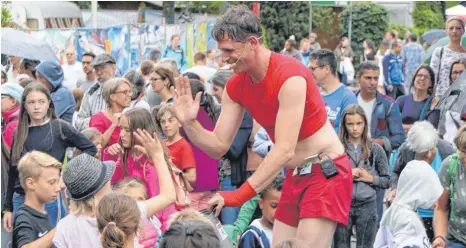  ?? FOTO: HARALD RUPPERT ?? Hier löst sich ein Stau auf: Ein Straßenkün­stler bekommt beim Kulturufer vor dem großen Zelt gutes Geld für eine gute Show.