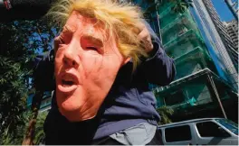  ??  ?? MANILA: A protester holding a Donald Trump mask, talks to the media following a brief protest at the Trump Tower hours after Trump was sworn in as the 45th President of the United States, yesterday in the financial district of Makati city. — AP photos