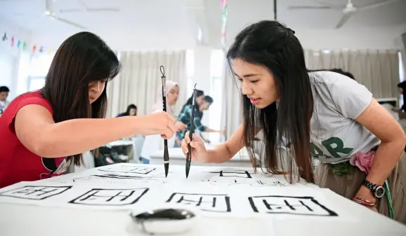  ??  ?? 16 participan­ts malaisiens au concours « Pont vers le chinois » calligraph­ient au pinceau les deux caractères signifiant « Chine » à l’Université normale de Hainan, le 27 octobre 2016.