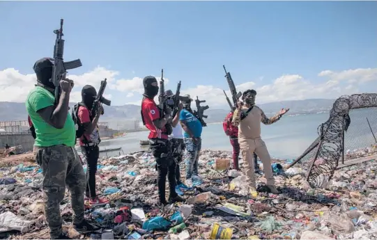  ?? RODRIGO ABD/AP PHOTOS ?? Flanked by members of the G9 gang coalition, leader Jimmy Cherizier, right, stands by the perimeter wall that encloses a Haitian port owned by the Mevs family.