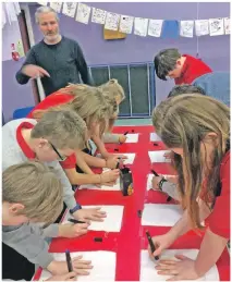  ??  ?? Pupils draw an outline of their hand on a piece of material which is used to make a banner.