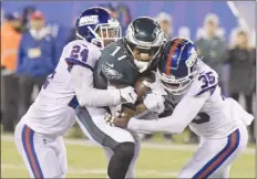  ?? The Associated Press ?? New York Giants’ Eli Apple (24) and Curtis Riley (35) tackle Philadelph­ia Eagles’ Alshon Jeffery (17) during first-half NFL action on Thursday night in East Rutherford, N.J. The Eagles won 34-13.