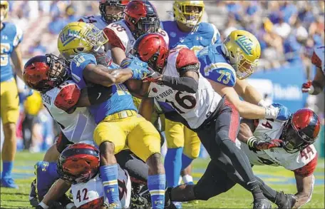  ?? Photograph­s by Robert Gauthier Los Angeles Times ?? UCLA RUNNING BACK Demetric Felton runs into a wall of San Diego State defenders at the line of scrimmage in the Bruins’ loss.