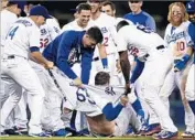  ?? Kevork Djansezian Getty Images ?? DODGERS TEAMMATES rip apart Kyle Farmer’s shirt after he hits a walk-off, two-run double.