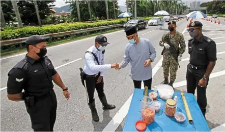  ?? — CHaN BOON KaI/the Star ?? Festive treat: Soffian sharing Hari raya goodies with personnel on duty during his visit to a checkpoint on the tun dr Lim Chong Eu Expressway.