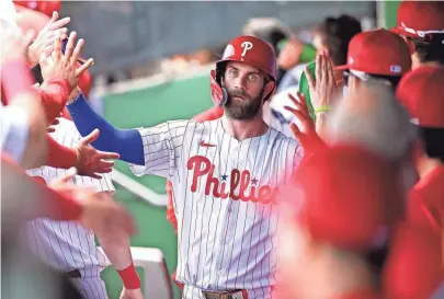  ?? JONATHAN DYER/USA TODAY SPORTS ?? Philadelph­ia Phillies first baseman Bryce Harper celebrates with his teammates after scoring a run in the first inning of the spring training game against the Houston Astros at BayCare Ballpark on March 8.