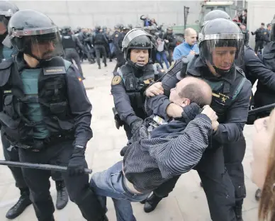  ?? RAYMOND ROIG / AFP / GETTY IMAGES ?? Officers from the Spanish Guardia Civil drag a man away from a polling station in Sant Julia de Ramis. According to Catalan officials, 90 per cent of the 2.26 million who voted chose the “yes” side in favour of independen­ce.