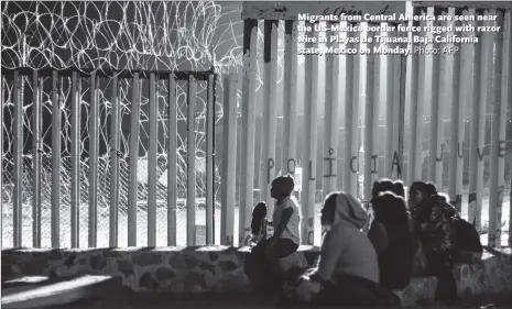  ?? Photo: AFP ?? Migrants from Central America are seen near the US-Mexico border fence rigged with razor wire in Playas de Tijuana, Baja California state, Mexico on Monday.