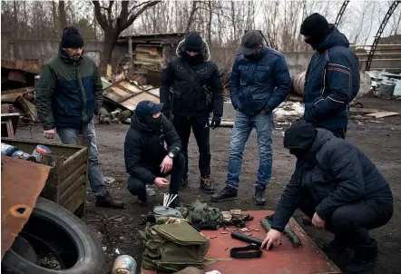  ?? AP ?? Roman, a former Ukrainian soldier wounded in combat, second from left, teaches civilians how to use weapons and urban warfare tactics during a training session at a junkyard on the outskirts of Lviv. Thousands of Ukrainian civilians have volunteere­d to help defend their country from invading Russian forces.