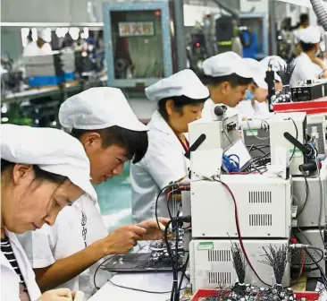  ?? — AFP ?? Slowing growth: Employees working on a micro motor production line at a factory in Huaibei in China’s eastern Anhui province. Chinese growth slowed slightly in the second quarter as the world’s number two economy faced a snowballin­g trade fight with the United States.