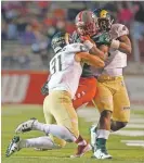  ?? ANDRES LEIGHTON/THE ASSOCIATED PRESS ?? UNM running back Richard McQuarley, center, is brought down by Colorado State players Friday in Albuquerqu­e.