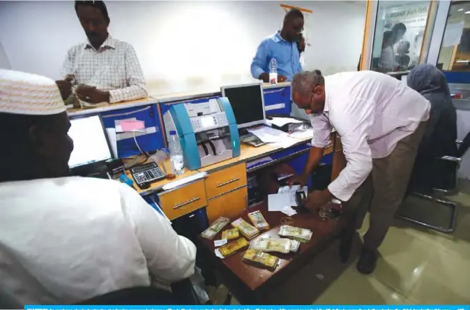  ??  ?? KHARTOUM: An employee checks banknotes at a foreign currency brokerage office in Khartoum yesterday. Sudan slashed the official value of its currency against the US dollar by more than half yesterday, the third devaluatio­n this year. — AFP