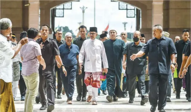  ?? Agence France-presse ?? ↑
Anwar Ibrahim (centre) leaves Putra Mosque after offering prayer in Putrajaya on Friday.