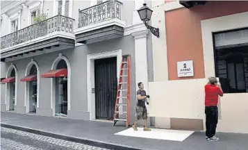  ?? CARL JUSTE/MIAMI HERALD/TNS ?? Handymen Daniel Hernandez, right, and Mario Baniaga work quickly Tuesday to board up the windows for a client’s storefront to prepare for Hurricane Maria’s arrival in Puerto Rico’s historic Old San Juan.