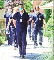  ?? Matthew Brown / Hearst Connecticu­t Media ?? Doctors of Greenwich Hospital Internal Medicine Residency Program walk to the gardens for a post graduation photo on June 12, 2020 in Greenwich. This is a group of doctors were pressed into service as rookies to help treat COVID patients in the ICU and for bedside care.