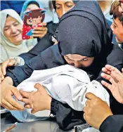  ??  ?? The mother of Leila al-ghandour cradles the corpse of her 8-month-old baby. Right, relatives mourn for Taher Ahmed Madi, 25, who was killed at the border fence