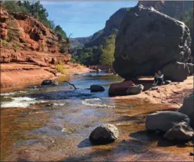 ?? JOSEPH GEDEON — THE ASSOCIATED PRESS ?? A visitor sits near Oak Creek in Slide Rock State Park near the town of Sedona, Ariz. The sleepy Arizona town of Sedona has long been a refuge for hikers, romantics and soul searchers.