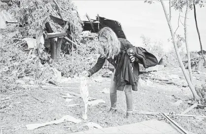  ?? JUSTIN TANG THE CANADIAN PRESS ?? Laurel Wingrove picks up her boyfriend’s belongings that were thrown outside their home by a tornado in Dunrobin, Ont., west of Ottawa.