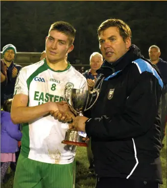  ??  ?? Evan Lavin , the Eastern Harps Captain is presented with the winners trophy. Pic: Tom Callanan.