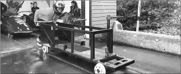  ??  ?? British Olympic bobsleigh hopefuls, including former profession­al rugby player Sam Blanchet, practice their starts at Bath University’s bobsleigh push track using a sled on rails, in Bath. — Reuters photo