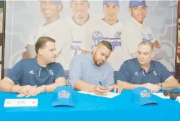  ??  ?? Adalberto Flores firma su contrato mientras es observado por los ejecutivos santurcino­s Frankie Higginboth­am (der.) y Joey Solá.