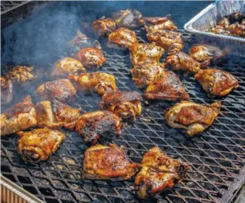  ?? STAFF FILE PHOTO BY DOUG STRICKLAND ?? Barbecue chicken cooks on a grill at the 2017 Ooltewah Barbecue Brawl at Cambridge Square. This year’s contest on Saturday will pit eight local barbecue teams in people’s choice and judges’ contests.