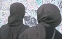  ?? TIM IRELAND/THE ASSOCIATED PRESS ?? Two women look at tributes Thursday near Grenfell Tower in London. A massive fire raced through the 24-story apartment, killing several.