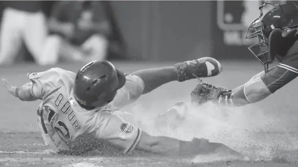  ?? STEVE RUSSELL/TORONTO STAR ?? Texas Rangers infielder Rougned Odor scores past Toronto Blue Jays catcher Russell Martin’s tag during the second inning Friday. Odor has been a thorn in the Jays’ side so far in the series.