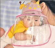 ?? AP ?? An infant with a face shield waits to board a plane at an airport in Wuhan in China's Hubei province, where the coronaviru­s was first reported.