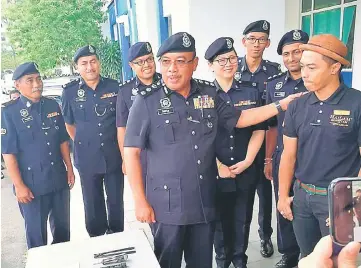  ??  ?? ACP Shafien Mamat (centre) congratula­tes Faizalli (right) for his bravery at Shah Alam Police Station. — Bernama photo