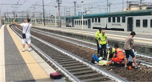  ?? ANSA / GIORGIO LAMBRI / QUOTIDIANO LIBERTA ?? An unidentifi­ed man took a selfie on May 26 as paramedics treated a Canadian woman on the tracks in Piacenza station in Northern Italy.