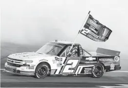  ?? RALPH FRESO AP ?? Sheldon Creed drives through the smoke from his burnout while holding a season champion banner after winning the NASCAR Truck Series race at Phoenix.