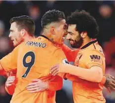  ?? Reuters ?? Liverpool’s Mohammad Salah celebrates scoring the second goal with Roberto Firmino and Andrew Robertson against Southampto­n at St Mary’s Stadium on Sunday.