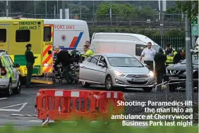  ??  ?? Shooting: Paramedics lift the man into an ambulance at Cherrywood Business Park last night