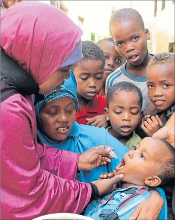  ??  ?? A child is given a polio vaccine in 2013 in Somalia, a country now poliovirus free. Below: John Primrose with wife Alison and children Taya and Thomas