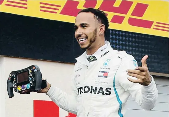  ?? JEAN-PAUL PELISSIER / REUTERS ?? Lewis Hamilton celebra su victoria con el volante de su monoplaza en la mano antes de acceder al podio