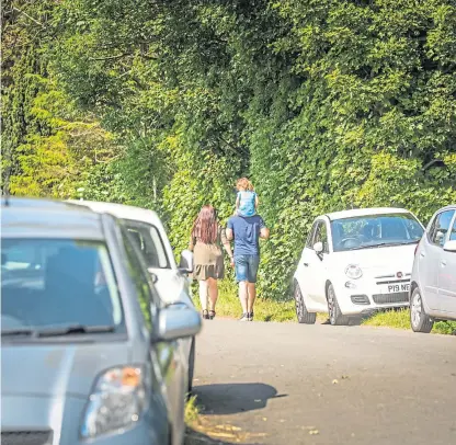  ?? Picture: Mhairi Edwards. ?? Sightseers walk past cars parked on grass verges near Lunan Bay.