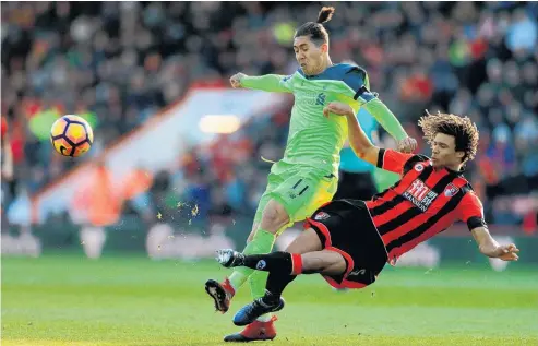  ?? Picture / AP ?? Bournemout­h had strong claims for a penalty turned down as Liverpool’s Roberto Firmino (left) challenges Nathan Ake.