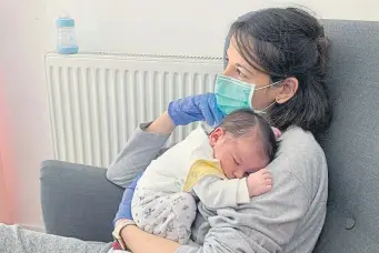  ?? Courtesy of the Carrillo-Muro family, AFP/Getty Images ?? Vanesa Muro holds her newborn son, Oscar Carrillo, on March 28 at their home in Madrid. For 10 days after giving birth, Muro was not allowed near her first child because she had tested positive for COVID-19.
