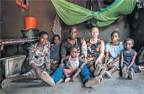  ??  ?? Femia Chulani, 47, third from right, a mother of nine, with her husband and some of her children, after she was the victim of an attempted kidnap plot. A gang tried to abduct Bertha Ngalande, 31, below, a teacher. Bottom, a banner promoting a witch doctor on the way to Mulanje, Malawi